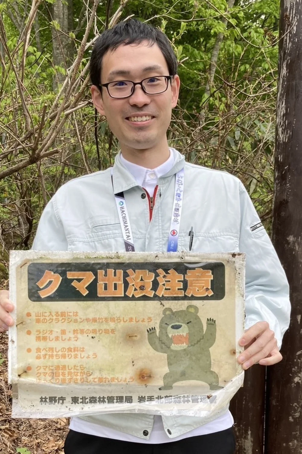 クマ出没注意の看板を持つ赤川竜之介